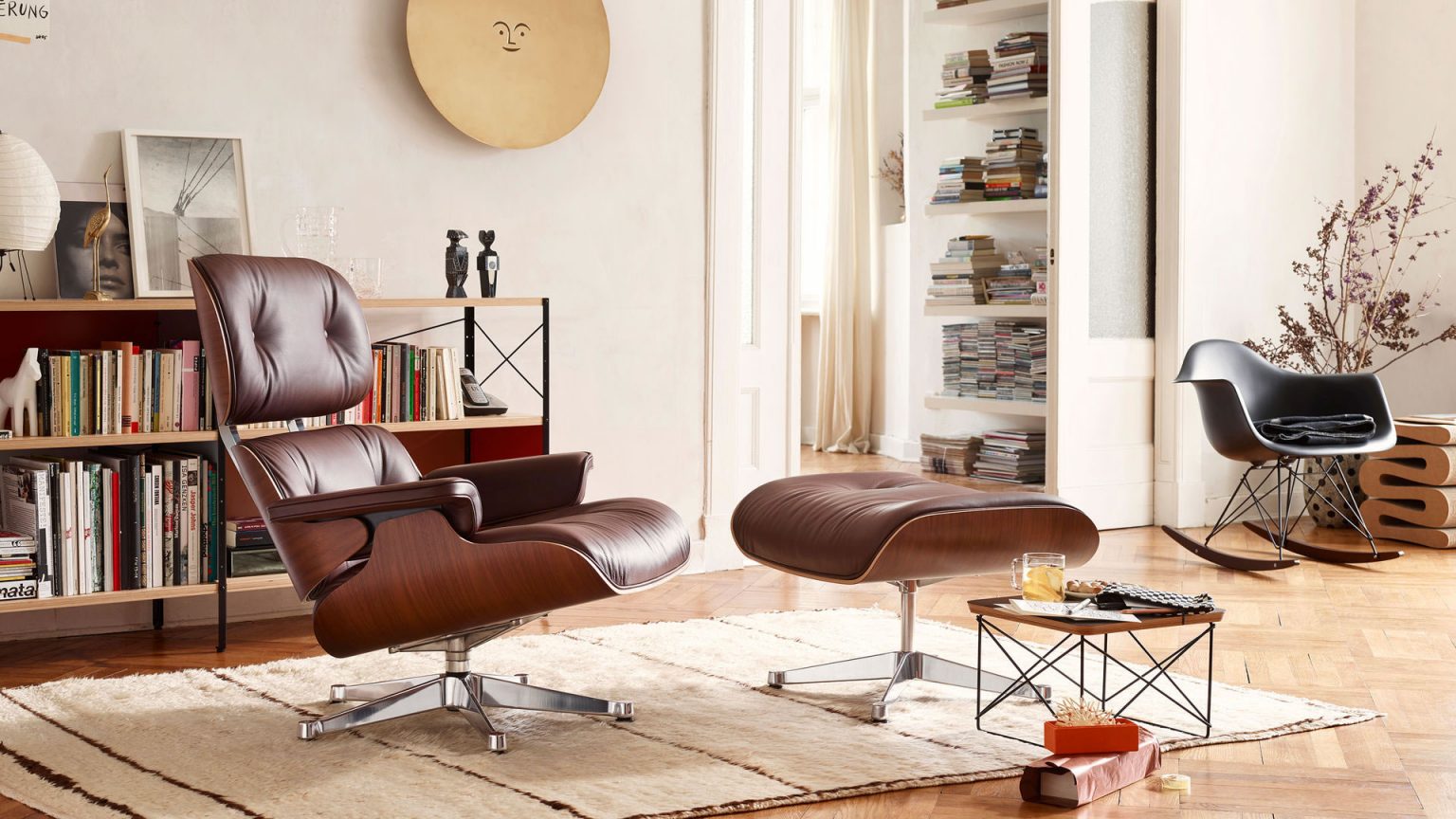 Eames Lounge Chair mit Ottoman aus Leder in modernem Wohnzimmer mit Bücherregal und Holzboden – Designmöbel bei Loeser Braunschweig