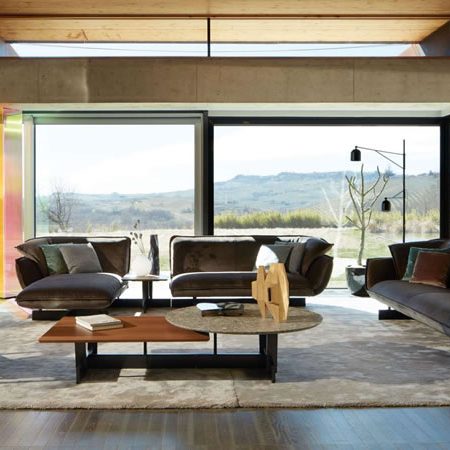 Großzügiges Wohnzimmer mit Cassina Sofas, Designer-Couchtischen und Panoramafenstern mit Blick auf die Landschaft – stilvolles Interieur im modernen italienischen Stil