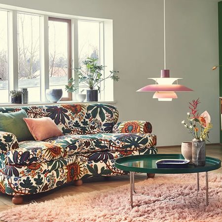 Wohnzimmer mit bunter Einrichtung, Louis Poulsen PH 5 Pendelleuchte und floraler Couch – harmonisches Zusammenspiel aus skandinavischem Design, Farbe und Licht