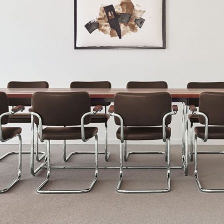 Thonet S 64 Freischwinger aus Leder mit verchromtem Stahlrohrgestell an einem Holztisch in modernem Besprechungsraum – zeitloser Designklassiker von Marcel Breuer