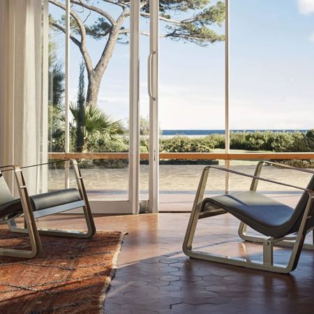 Zwei Vitra Repos Lounge Chairs mit Lederbezug und Aluminiumgestell in lichtdurchflutetem Raum mit Meerblick – elegantes Interieur für entspanntes Wohnen
